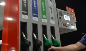 Dłoń sięga po dystrybutor z napisem DIESEL. Na stacji paliw można wybrać różne rodzaje paliwa, w tym diesel.