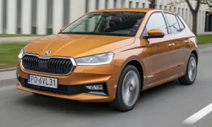 Pomarańczowa Skoda Fabia 2021 pędzi po drodze, jej reflektory ostro świecą, a felgi wirują w ruchu.