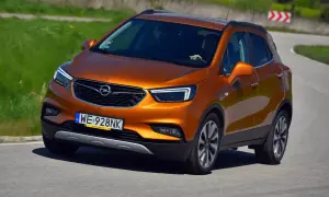 Pomarańczowy Opel Mokka 2015 na zakręcie drogi.