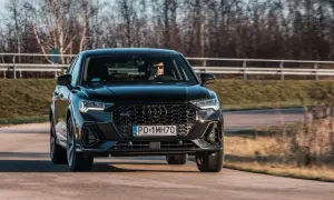 Czarny q3 audi pędzi po drodze, kierowca w okularach obserwuje trasę.