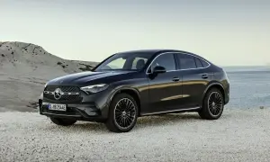 Elegancki, czarny Mercedes-Benz GLC Coupe stoi na kamienistej plaży, z widokiem na spokojne morze.