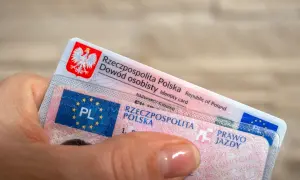 Dłoń trzyma polski dowód osobisty i prawo jazdy. To ważne dokumenty, które pozwalają na legalne poruszanie się po drogach, a niektóre z nich, jak prawo jazdy bezterminowe, są ważne przez całe życie.