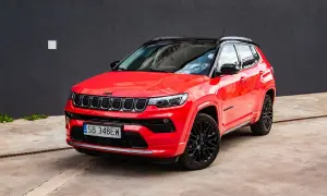 Czerwony Jeep Compass z czarnym dachem i felgami. Zbliżenie na przód auta, gdzie widoczne są charakterystyczne siedmioszczelinowe wloty powietrza. Idealny do miasta i na wyprawy, jego wymiary są dopasowane do potrzeb kierowców.