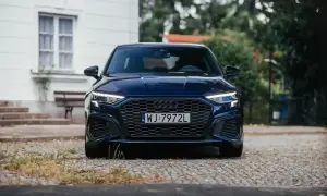 Granatowy Audi A3, segment c, z charakterystycznym grillem i ostrymi światłami, zaparkowany na brukowanej drodze.