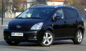 Czarny Toyota Verso z polskimi tablicami WE 1606F zaparkowany na ulicy.