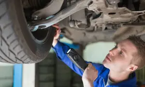 Mechanik z latarką bada podwozie auta. Czy to znak, że nastąpił brak przeglądu powyżej 30 dni?