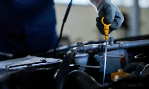 Mechanik w rękawiczce wyciąga żółtą miarkę, sprawdzając poziom oleju. To ważny element kontroli, by odma olejowa działała prawidłowo.