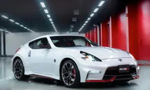 Biały Nissan 370Z Nismo z czerwonymi akcentami, lśniący w garażu z czerwonymi ścianami i rzędem świateł na suficie.