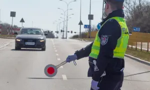 Policjant kieruje ruchem, zatrzymując samochód. Może to być kontrola drogowa lub kurs reedukacyjny.