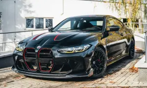 Czarny BMW M4 CSL z czerwonymi akcentami na masce i grillu, zaparkowany na brukowanej nawierzchni.