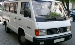 Biały Mercedes MB 100 D, klasyczny van, zaparkowany na ulicy.