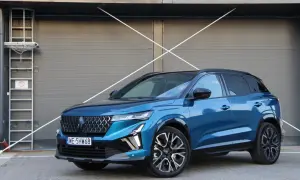 Błękitny Renault Austral 2025 z czarnym dachem i felgami stoi przed szarą, nowoczesną bramą.