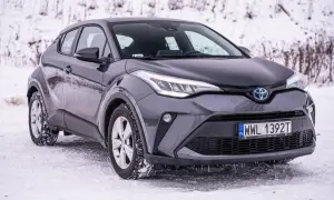 Szary Toyota C-HR Hybrid na śniegu, gotowy na zimowe wyzwania.