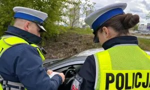Policjanci w kamizelkach odblaskowych sprawdzają dokumenty, być może wystawiają mandaty za prędkość.