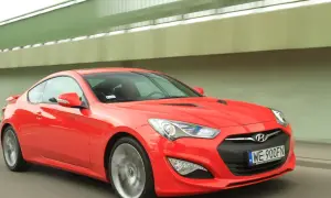 Czerwony Hyundai Genesis Coupe 3.8 V6 w ruchu, z widocznym kierowcą i tablicą rejestracyjną WE 900FN.