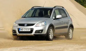 Srebrny Suzuki SX4 1.6 benzyna pokonuje piaszczystą wydmę, wzbijając tumany kurzu.