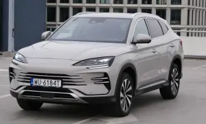 Nowy BYD Song Plus, elegancka hybryda SUV, prezentuje się na parkingu przed nowoczesnym budynkiem.