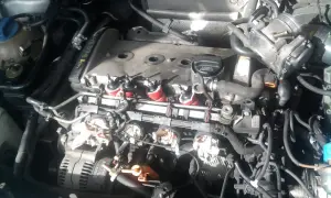 Silnik Audi A4 B6 2.0 benzyna w trakcie prac. Widoczne cewki zapłonowe, przepustnica i alternator.