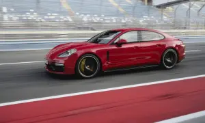Czerwone Porsche Panamera GTS pędzi po torze wyścigowym, za nim widać trybuny.