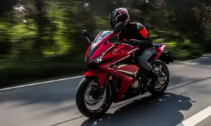 Motocyklista w kasku i kurtce jedzie sportowym, czerwonym motocyklem. Idealny sprzęt na pierwsze prawo jazdy a2.