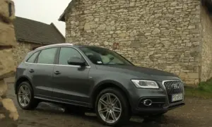 Szary Audi Q5 Quattro zaparkowany przy kamiennym budynku.
