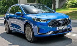 Niebieski Ford Kuga 2025 pędzi po drodze, otoczony zielenią.