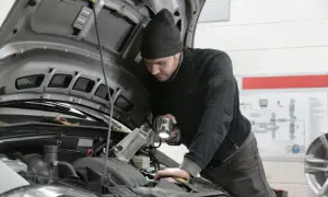 Mechanik z latarką bada silnik Renault, szukając przyczyny błędu DTC P0380.