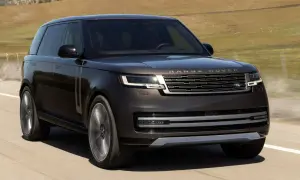 Elegancki, ciemnobrązowy Range Rover 2025 pędzi po pustej drodze, otoczony suchymi, pagórkowatymi krajobrazami.