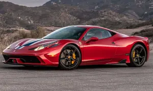 Czerwone Ferrari 458 z białymi i niebieskimi pasami na masce, zaparkowane na tle górskiego krajobrazu.