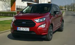 Czerwony Ford Ecosport z czarnym dachem jedzie po miejskiej drodze.