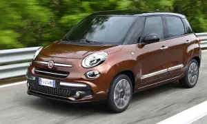 Brązowy Fiat 500L z czarnym dachem pędzi po drodze, otoczony zielenią.