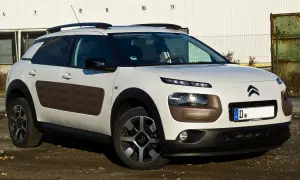 Biały Citroen Cactus z brązowymi wstawkami Airbump na drzwiach, zaparkowany na brudnym podjeździe.