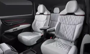 Wnętrze Audi Q9: luksusowe, białe fotele z pikowanymi wstawkami i czerwonymi akcentami. Komfort i styl.