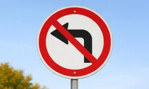 Znak drogowy: zakaz skrętu w lewo. Nie można skręcać w lewo, trzeba jechać prosto lub w prawo.