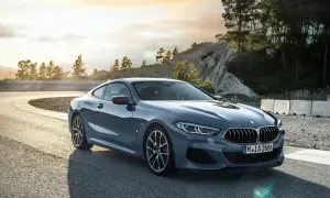 Szary BMW 840d na zakręcie toru wyścigowego, z drzewami i skalistym zboczem w tle.