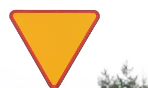 Żółty trójkąt z czerwoną obwódką, znak ustąp pierwszeństwa, ostrzega przed zbliżającym się skrzyżowaniem.