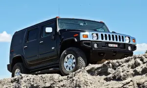 Czarny Hummer H2 pokonuje skalisty teren pod błękitnym niebem.