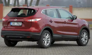 Czerwony Nissan Qashqai 2. generacji z czeskimi tablicami rejestracyjnymi stoi na brukowanym placu.