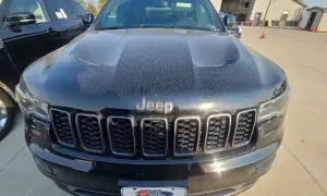 Czarny Jeep Limited, pokryty kurzem, z charakterystycznym grillem i logo Jeep.