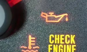Czerwona kontrolka oleju świeci się na desce rozdzielczej. Obok widać ikonę termometru i napis "CHECK ENGINE".