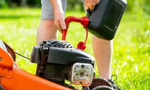 Mężczyzna nalewa paliwo do kosiarki. Prawidłowe paliwo do kosiarki to klucz do jej sprawnego działania.
