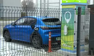 Niebieski samochód elektryczny podłączony do ładowarki. Zastanawiasz się, ile waży samochód elektryczny? Ten model jest lekki i ekologiczny.