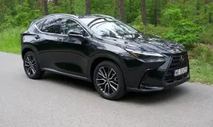 Czarny Lexus NX 350h na tle leśnej drogi. Elegancki SUV z charakterystycznym grillem i nowoczesnymi światłami.