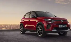 Nowy, czerwony Citroen C3 2025 z czarnym dachem i felgami, zaparkowany na tle miasta o zachodzie słońca.