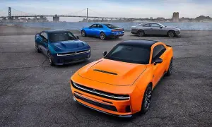 Pomarańczowy i niebieski Dodge Hellcat z innymi autami na tle mostu i miasta.