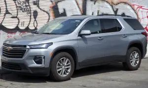 Szary Chevrolet Traverse SUV zaparkowany przed ścianą z graffiti.