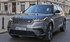 Szary Range Rover Velar jedzie ulicą w mieście. Kierowca jest widoczny za kierownicą.