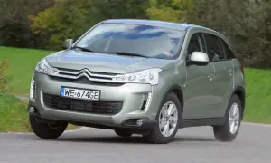 Zielony Citroen C4 Aircross z polskimi tablicami WE 674GE jedzie po drodze wśród zieleni.