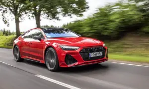 Czerwone Audi RS 7 pędzi po drodze, otoczone zielenią drzew.