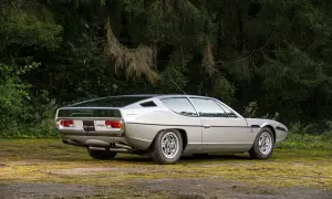 Srebrny Lamborghini Espada z lat 70. na tle zieleni. Klasyk motoryzacji.